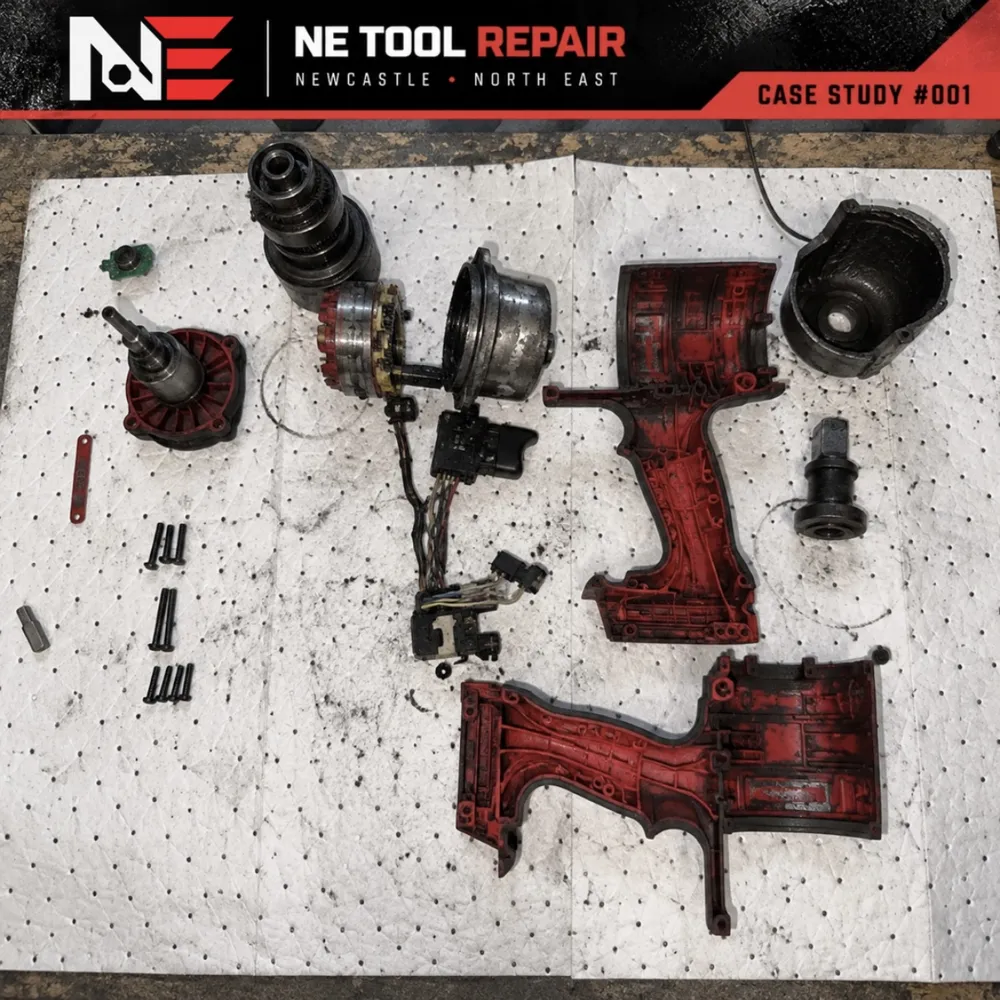 Milwaukee M18 impact wrench fully stripped down on the bench, with internals laid out for cleaning