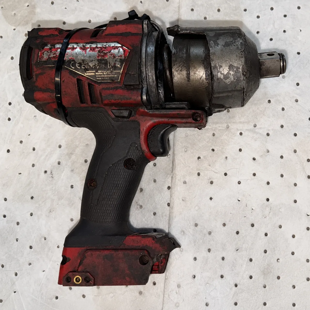 Worn Milwaukee M18 FUEL impact wrench before refurbishment, with scuffed red housing and tarnished nose